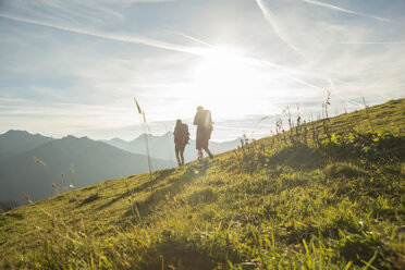 Österreich, Tirol, Tannheimer Tal, junges Paar wandert auf Almwiese - UUF002228