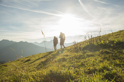Österreich, Tirol, Tannheimer Tal, junges Paar wandert auf Almwiese - UUF002228