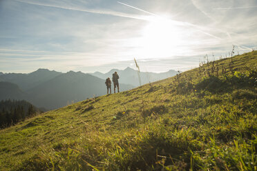 Österreich, Tirol, Tannheimer Tal, junges Paar wandert auf Almwiese - UUF002229