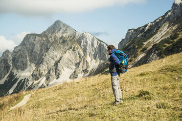 Österreich, Tirol, Tannheimer Tal, Wanderer mit Rucksack auf Almwiese - UUF002234