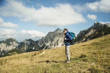 Österreich, Tirol, Tannheimer Tal, Wanderer mit Rucksack auf Almwiese - UUF002235