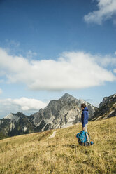 Österreich, Tirol, Tannheimer Tal, Wanderer mit Rucksack auf Almwiese - UUF002236