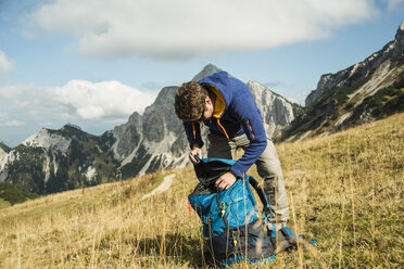 Österreich, Tirol, Tannheimer Tal, Wanderer mit Rucksack auf Almwiese - UUF002238