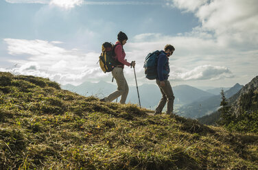 Österreich, Tirol, Tannheimer Tal, junges Paar wandert auf Almwiese - UUF002253