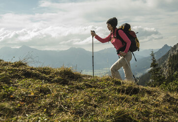 Austria, Tyrol, Tannheimer Tal, young woman hiking on alpine meadow - UUF002254