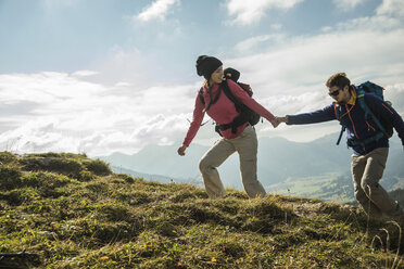 Austria, Tyrol, Tannheimer Tal, young couple hiking hand in hand on alpine meadow - UUF002256