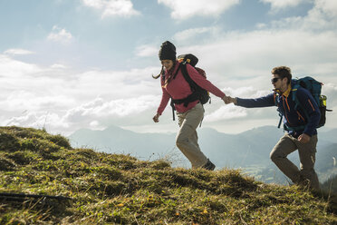 Österreich, Tirol, Tannheimer Tal, junges Paar wandert Hand in Hand auf Almwiese - UUF002258