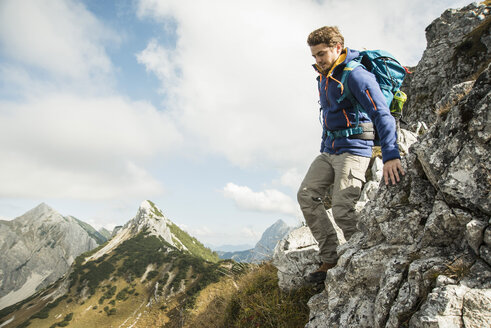 Österreich, Tirol, Tannheimer Tal, junger Mann wandert auf Fels - UUF002269