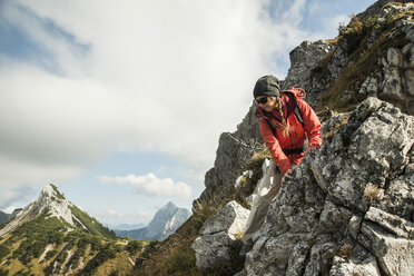 Österreich, Tirol, Tannheimer Tal, junge Frau wandert auf Felsen - UUF002270