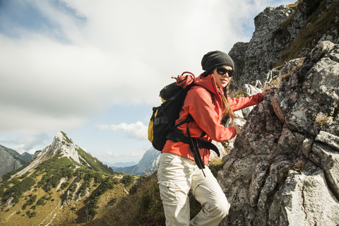 Österreich, Tirol, Tannheimer Tal, junge Frau wandert auf Felsen, lizenzfreies Stockfoto