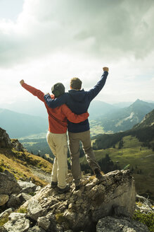 Austria, Tyrol, Tannheimer Tal, young couple cheering on mountain top - UUF002285