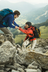 Österreich, Tirol, Tannheimer Tal, junges Paar beim Wandern auf Felsen - UUF002289