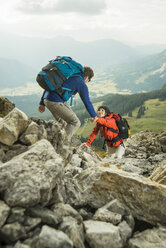 Österreich, Tirol, Tannheimer Tal, junges Paar beim Wandern auf Felsen - UUF002290