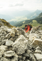 Österreich, Tirol, Tannheimer Tal, junge Frau klettert auf Felsen - UUF002292