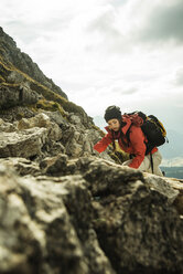 Österreich, Tirol, Tannheimer Tal, junge Frau klettert auf Felsen - UUF002294