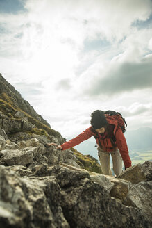 Österreich, Tirol, Tannheimer Tal, junge Frau klettert auf Felsen - UUF002295