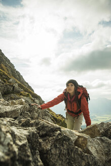 Österreich, Tirol, Tannheimer Tal, junge Frau klettert auf Felsen - UUF002296