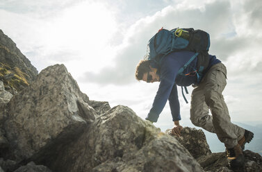 Austria, Tyrol, Tannheimer Tal, young man climbing on rock - UUF002223
