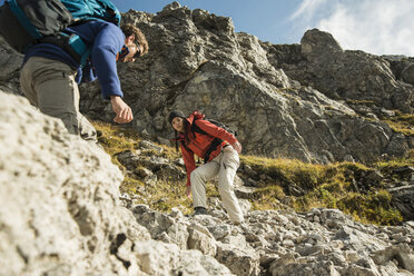 Österreich, Tirol, Tannheimer Tal, junges Paar beim Wandern auf Felsen - UUF002219