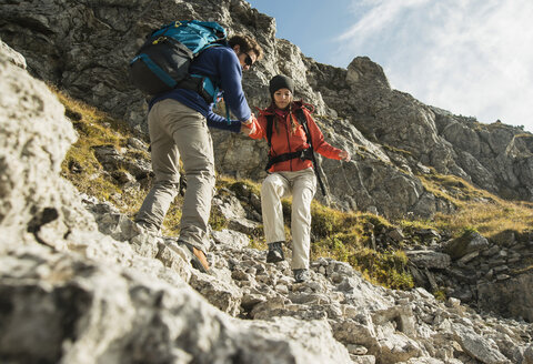Österreich, Tirol, Tannheimer Tal, junges Paar beim Wandern auf Felsen - UUF002218