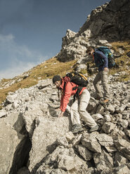 Österreich, Tirol, Tannheimer Tal, junges Paar beim Wandern auf Felsen - UUF002217