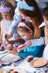 Teenage girl and girls garnishing cupcakes on a birthday party - ZEF001368