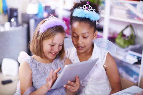 Zwei Mädchen benutzen ein digitales Tablet auf einer Geburtstagsparty, lizenzfreies Stockfoto