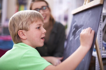 Boy writing formula on blackboard - ZEF001427