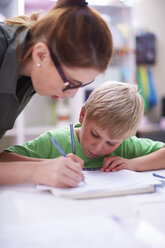 Lehrer schaut auf einen schreibenden Schüler - ZEF001429