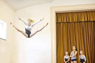 Mädchen im Gymnastik-Outfit macht Luftsprung mit drei Mädchen beobachten - ZEF002130