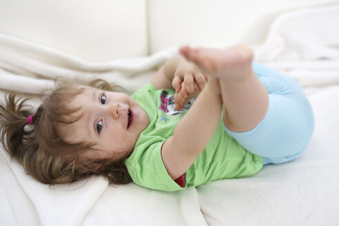 Entspanntes Babymädchen auf weißer Decke liegend - SHKF000016