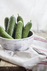 Bowl of mini cucumbers on cloth and wood - SBDF001333