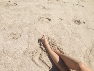 Female legs in the sand at a beach in Mexico - ABAF001517