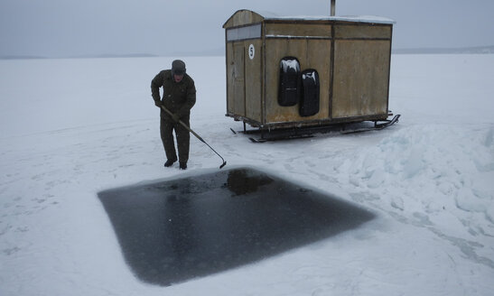 Russland, Polarkreis-Tauchzentrum, Polarkreis, Weißes Meer, Mann bereitet Loch für Eistauchen vor - GNF001317