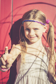 Porträt eines lächelnden kleinen Mädchens im Sommer mit Siegeszeichen - SARF000923