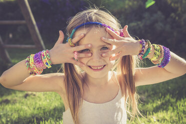 Portrait of smiling ittle girl showing her loom bracelets - SARF000918