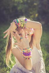 Portrait of little girl showing her loom bracelets and rings - SARF000917