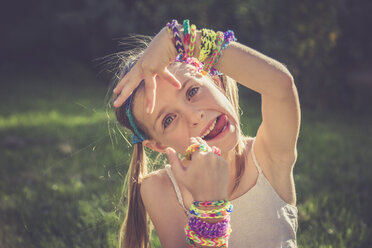 Portrait of little girl with outstretched tongue showing her loom bracelets and rings - SARF000916