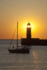 Germany, Bremen, Bremerhaven, Sailing booat, Lighthouse on the pier at sunset - OLEF000043