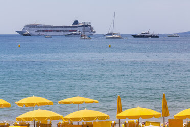 France, Cote d'Azur, Cannes, beach umbrellas on beach and cruse ship on the ocean - WDF002715