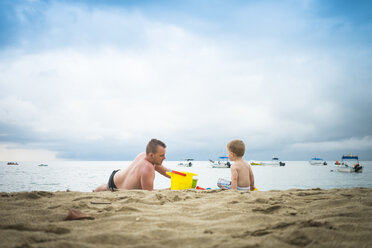 Mexiko, Vater spielt mit seinem kleinen Sohn im Sand am Strand - ABAF001527