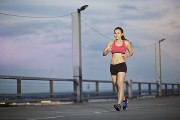 Young female Asian sportswoman jogging at twilight - MAD000092