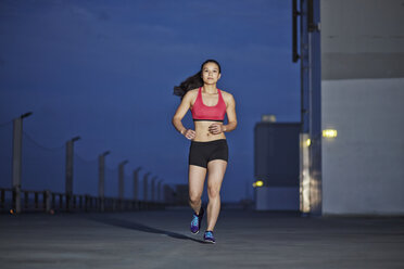 Junge asiatische Sportlerin beim Joggen in der Dämmerung - MAD000093