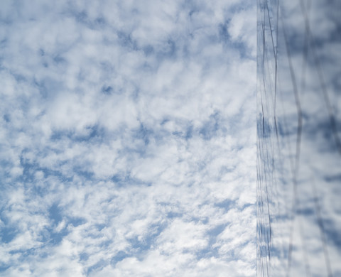 Wolken spiegeln sich in einer Glasfassade eines Hochhauses, lizenzfreies Stockfoto