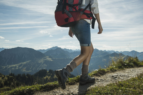 Österreich, Tirol, Tannheimer Tal, junge Frau wandert auf Bergpfad, lizenzfreies Stockfoto