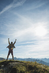 Austria, Tyrol, Tannheimer Tal, young man cheering on mountain top - UUF002183