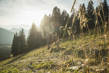 Österreich, Tirol, Tannheimer Tal, junges Paar wandert im Sonnenlicht auf Almwiese - UUF002148