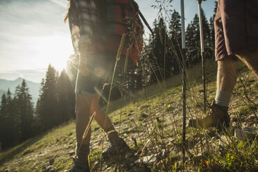 Österreich, Tirol, Tannheimer Tal, junges Paar wandert im Sonnenlicht auf Almwiese - UUF002146