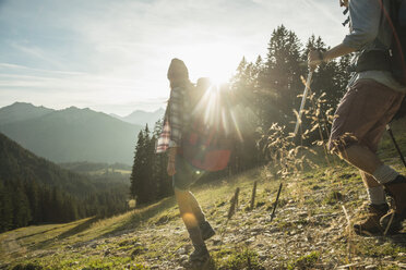 Austria, Tyrol, Tannheimer Tal, young couple hiking in sunlight on alpine meadow - UUF002210
