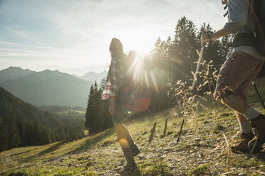 Österreich, Tirol, Tannheimer Tal, junges Paar wandert im Sonnenlicht auf Almwiese - UUF002210